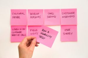 To rows of pink post it notes with brand development plan written on